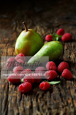 Pears and raspberries on old wooden surface