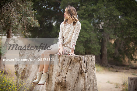 Woman sitting on tree trunk in park, Stoney Point, Topanga Canyon, Chatsworth, Los Angeles, California, USA