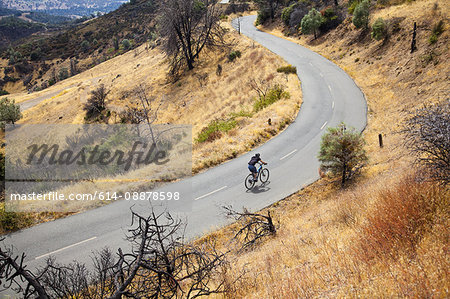 Young male mountain biker riding uphill on rural road, Mount Diablo, Bay Area, California, USA