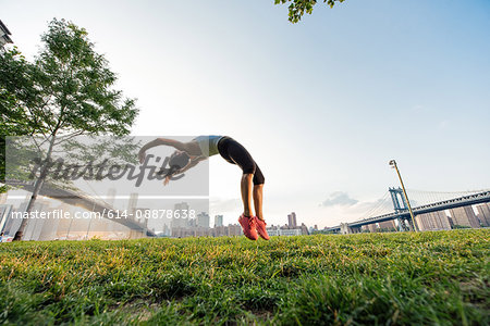 Young woman doing backflips in park, New York, USA