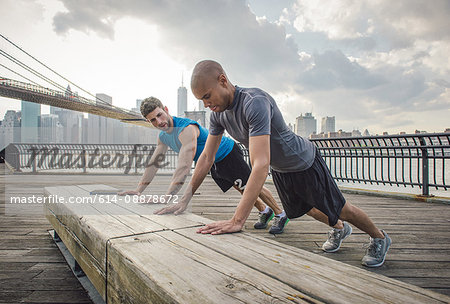 Two young men training on riverside bench, Brooklyn, New York, USA