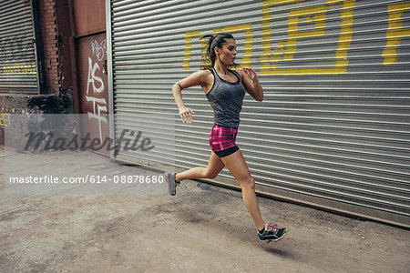 Young female runner running in city street