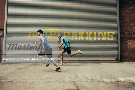 Two young male runners running on city street