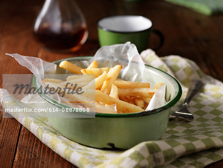 French fries in vintage bowl on tea towel, with vinegar bottle