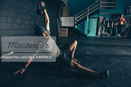 Male crossfitter lifting kettlebell in  gym