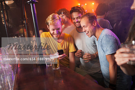 Group of friends smiling at smartphone in club