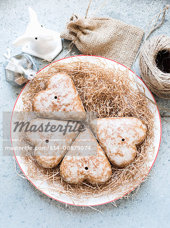 Overhead view of heart shaped gingerbread biscuits on straw covered plate