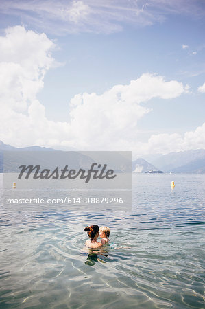 Head and shoulders of mother holding son in lake, Luino, Lombardy, Italy