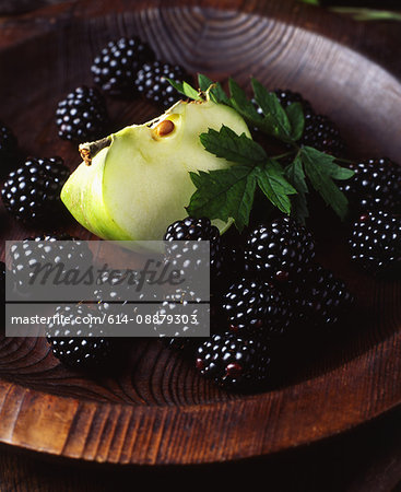 Fresh green apple slice and blackberries in wooden bowl