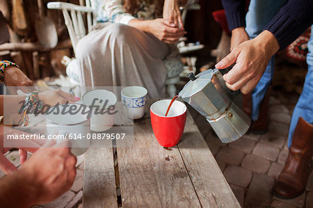 Cropped shot of adult friends pouring coffee in cabin