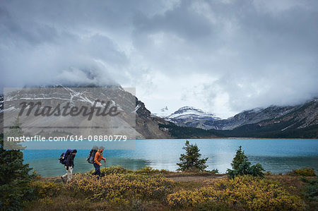 Hikers hiking by lake and snow capped mountains, Banff, Alberta, Canada