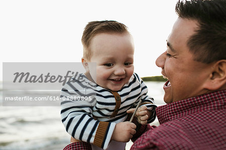 Father on beach holding smiling baby boy