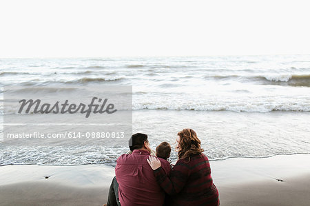 Rear view of mother and father sitting on beach