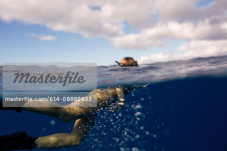 Woman wearing flippers swimming underwater, Oahu, Hawaii, USA