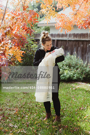 Mid adult woman carrying newborn baby daughter in garden