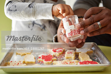 Father and daughter decorating unbaked cookies, close-up