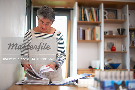 Senior woman in kitchen, looking through file