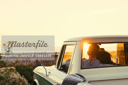 Rear view of couple in pickup truck watching sunset at Newport Beach, California, USA