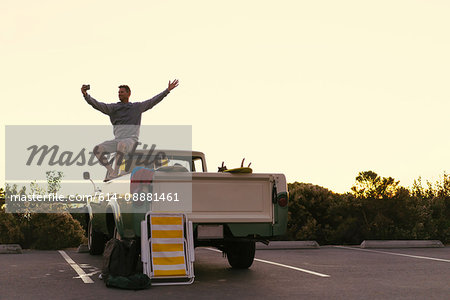 Man taking smartphone selfie in back of pickup truck at Newport Beach, California, USA