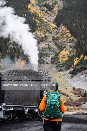 Tourist walking in mountain and looking at steam locomotive