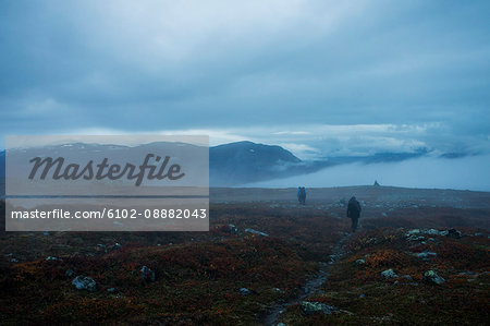 People walking down meadow on cloudy day