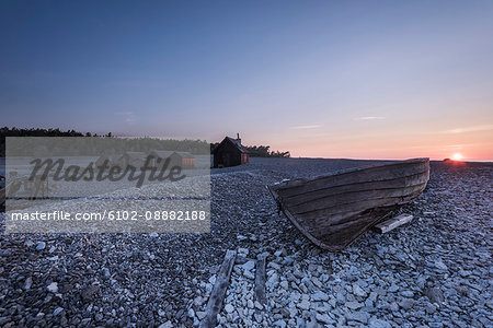 Wooden boat on rocky beach at sunset