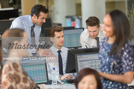 Businessmen working at computer in open plan office