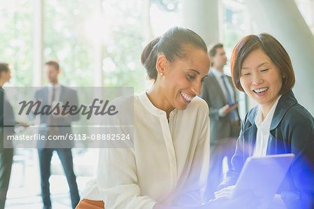 Businesswomen using digital tablet in office lobby