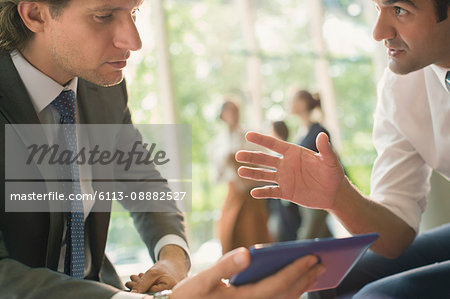 Businessmen with digital tablet talking