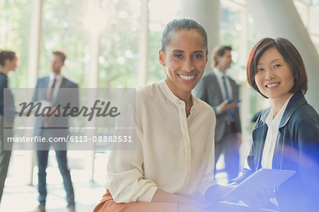 Portrait smiling businesswomen with digital tablet in office lobby