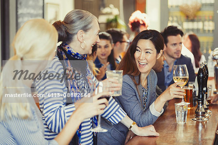 Smiling women friends drinking wine at bar