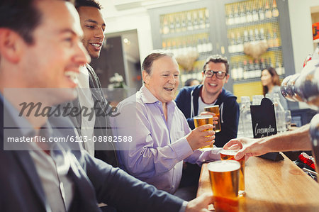 Smiling men friends drinking beer at bar