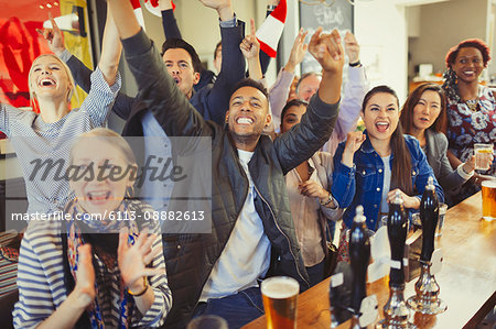 Enthusiastic sports fans cheering and watching game at bar