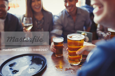 Friends drinking beer and wine at table in bar