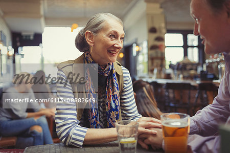 Affectionate couple holding hands and drinking beer at table in bar