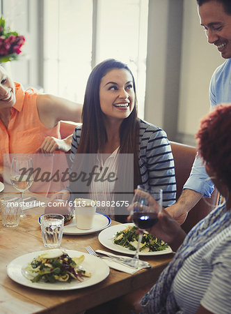 Waiter serving salads to women dining at restaurant table