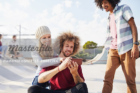 Friends using smart phone at sunny skate park