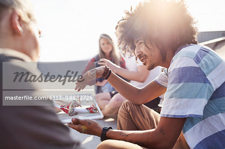 Friends using digital tablet at sunny skate park