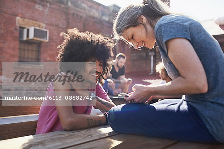 Couple texting with cell phone on sunny urban rooftop