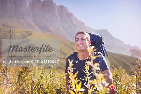 Young man with backpack hiking in sunny valley