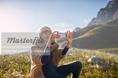 Young woman using camera phone in sunny, remote valley