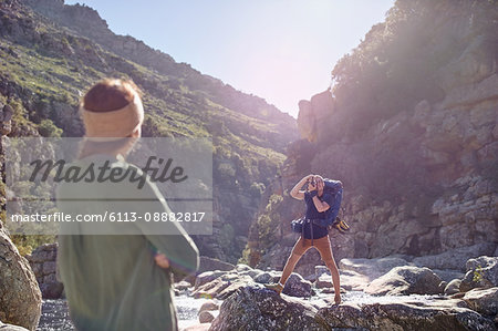 Young woman watching boyfriend hiking, photographing craggy cliffs