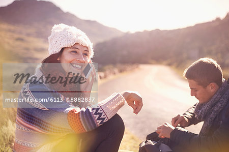 Smiling young woman talking on cell phone at sunny, remote roadside