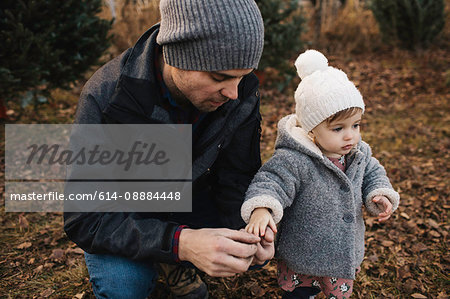 Father holding hand of baby girl in forest