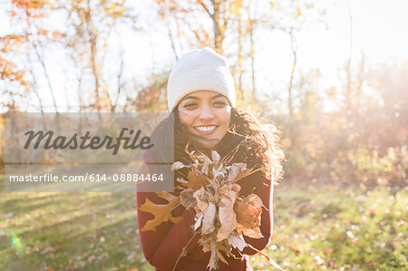 Portrait of young woman holding autumn leaves