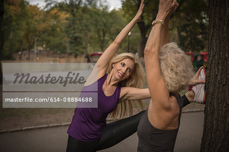 Two mature female friends training in park, stretching