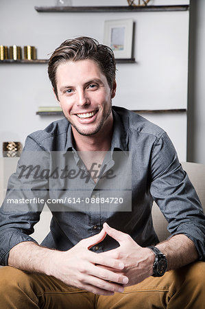Portrait of young man sitting on sofa, smiling