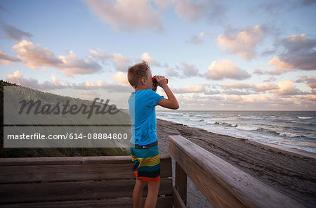 Boy at beach looking at view through binoculars, Blowing Rocks Preserve, Jupiter, Florida, USA