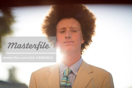 Portrait of teenage boy with red afro hair, wearing suit, outdoors