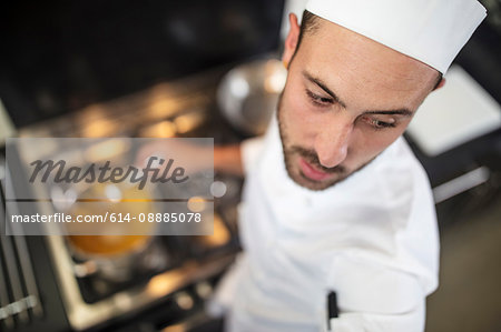 Chef stirring pan on stove, elevated view